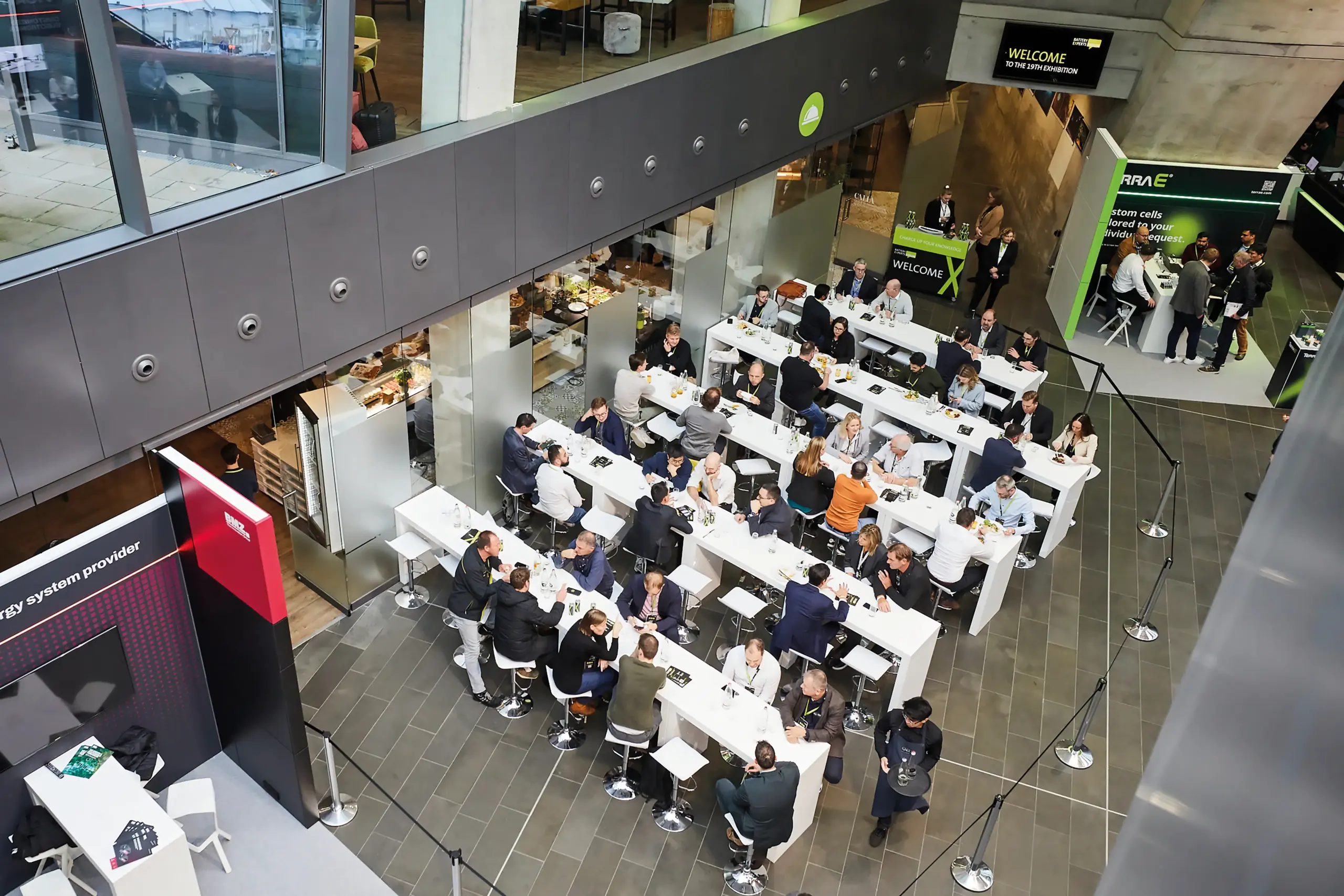 Teilnehmer:innen des Battery Experts Forum sitzen an langen Tischen im offenen Veranstaltungsbereich und tauschen sich während des Networking-Events aus.