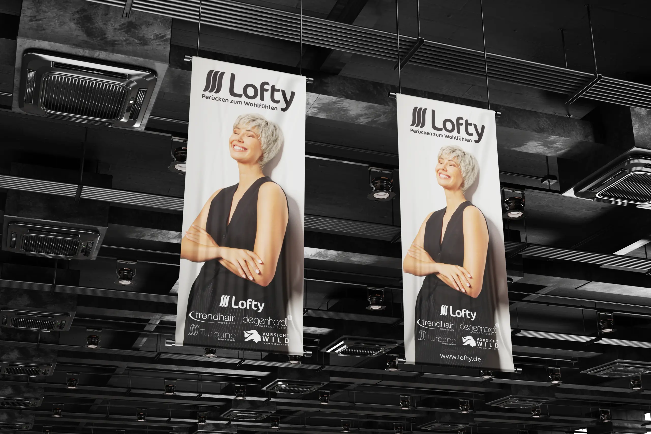 Großformatige Lofty-Hängebanner mit Modelaufnahme und Markenlogo in moderner Innenraumumgebung. Die Banner übertragen das Corporate Design aufmerksamkeitsstark auf Werbe- und Präsentationsflächen.